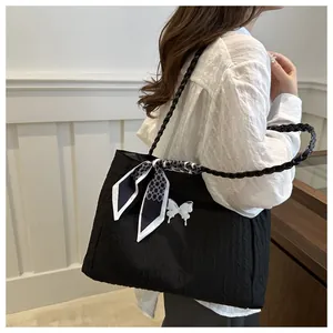 Detail of black pleated tote bag with white butterfly buckle and patterned silk scarf
