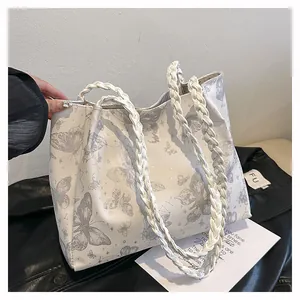 Detail of white tote bag featuring gray butterfly prints and thick woven rope handles