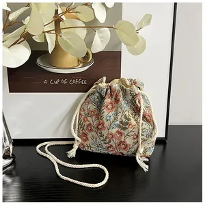 Detail of floral tapestry canvas bucket bag with cotton drawstring on a wooden desk