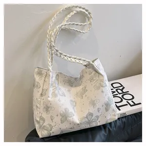 Detailed view of white tote bag with green butterfly and constellation prints and woven handles