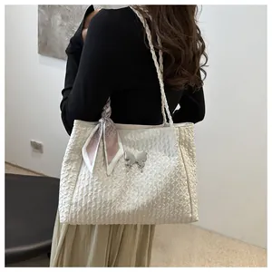 Close-up of white pleated tote bag with silver butterfly pendant and floral scarf detail