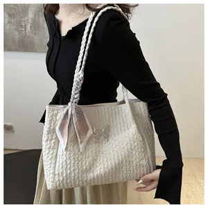 Detail of white pleated tote bag with silver butterfly charm and pink silk scarf wrap handle