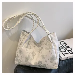 Close-up of white tote bag featuring butterfly patterns and woven rope shoulder straps