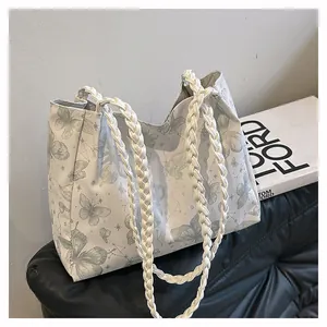 Detailed shot of white canvas tote bag with butterfly prints and thick woven handles