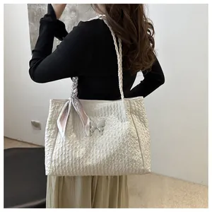 Detail view of white tote bag with textured pleats, silver butterfly, and silk scarf
