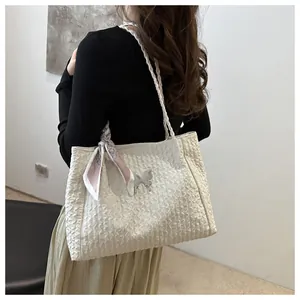 Close-up of white tote bag featuring pleated texture and silver butterfly metal charm
