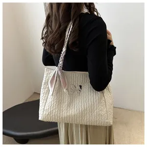 Detail of cream bubble textured tote bag with silver butterfly charm and floral silk scarf