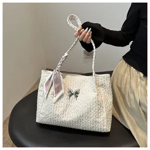 Close-up of white textured tote bag with silver butterfly charm and lavender scarf accent
