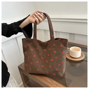 Close-up of deep brown corduroy tote bag with cute red strawberry print and soft texture