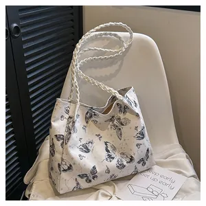 Detail of white tote bag with black celestial patterns and woven handles in a lifestyle setting