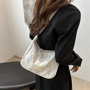 White textured nylon shoulder bag with colorful embroidery and a wide beige strap