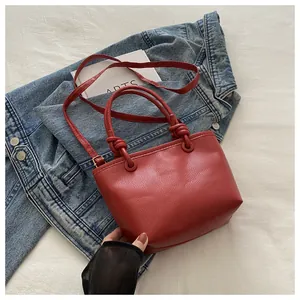 Detailed macro view of dark red lychee grain leather bucket bag with twist knot handles