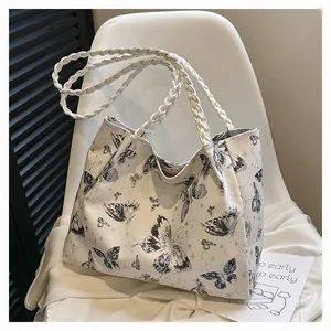 Detail of white tote bag featuring black butterfly prints and woven rope handles
