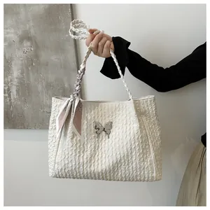 Detail of white tote bag with bow buckle, woven handle and silk scarf accessory