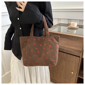 Detail of vintage brown corduroy tote bag featuring red strawberry patterns for women