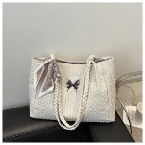 Close-up of white tote bag with woven texture, silver butterfly charm and patterned scarf