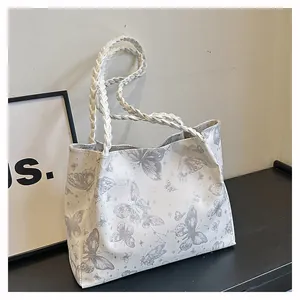 Detail of white tote bag with grey butterfly print and white braided woven handles