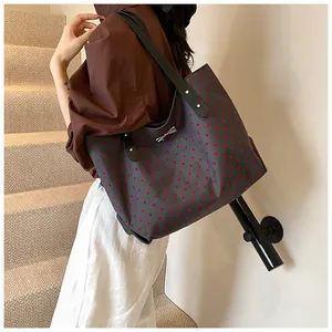 Detail of metal bow accent and red heart print on a large capacity tote bag