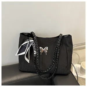 Detailed texture of black pleated tote bag with silver butterfly clasp and woven handle