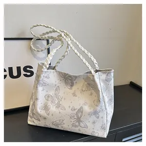 Close-up of white tote bag featuring gray butterfly prints and braided rope straps