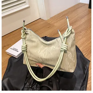 Detail of hobo bag showing pleated texture, knotted rope handle, and metal closures