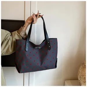 Detail of dark grey polka dot canvas tote bag with black straps and silver bow accent