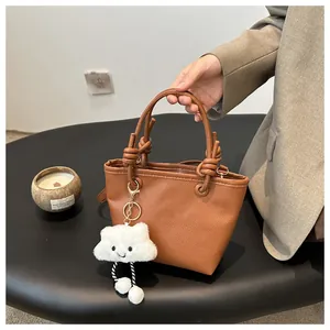 Detailed shot of brown lychee grain mini bucket bag with woven knot handle and cloud charm