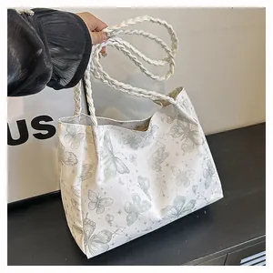 Detailed view of woven rope handle and butterfly print on stylish white tote bag