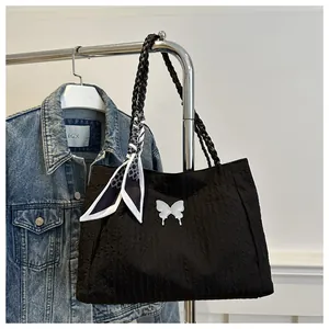Detail of black pleated tote bag with white butterfly motif and silk scarf on a hanger