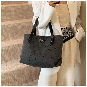 Detail of grey canvas tote bag with star prints and a golden bow on a fashion model