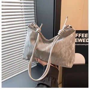 Detail of silver metallic tote bag featuring pleated texture and knotted shoulder strap