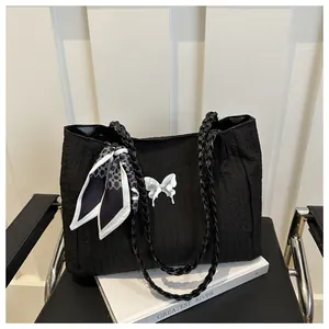 Detail of black pleated tote bag with silver butterfly buckle and floral silk scarf