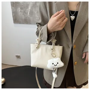 Detail of cream white leather bucket bag with rope handle and cloud plush charm decoration