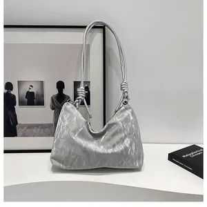 Detail of silver metallic hobo bag featuring crinkled texture and decorative knot strap