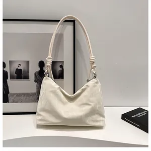Detail of cream white shoulder bag with textured material and decorative rope knot strap