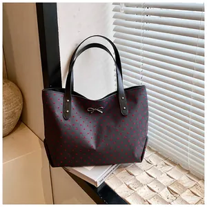 Detail of grey tote bag with red heart patterns, bow accessory and leather straps