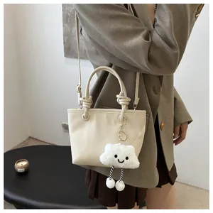 Close-up of cream bucket bag featuring a plush cloud charm and fine lychee leather texture