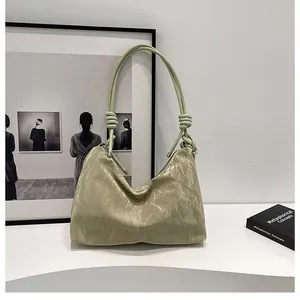 Detail of light green pleated shoulder bag with decorative knotted strap and soft texture