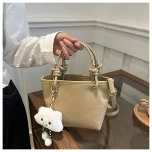 Close-up of litchi grain leather bucket bag with knot handles and cute cloud charm