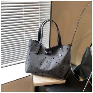 Detail of star pattern canvas tote bag with a silver bow and leather handles