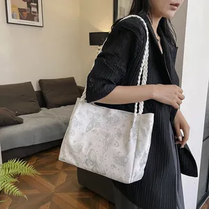 Canvas tote bag with butterfly print and woven straps shown on shoulder for daily commute