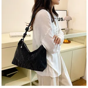 Detail of black pleated shoulder bag featuring unique knotted strap for a modern chic look