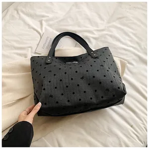 Close-up of dark grey tote bag with black polka dots and silver bow detail on fabric