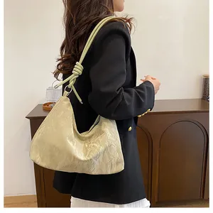Detail of beige pleated hobo bag featuring decorative knot shoulder strap and soft texture
