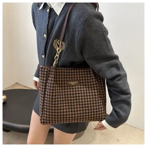 Detail of vintage houndstooth tote bag featuring leather logo patch and gold chain strap