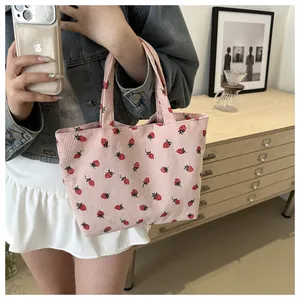 Close-up of pink corduroy tote bag featuring red strawberry patterns and soft texture