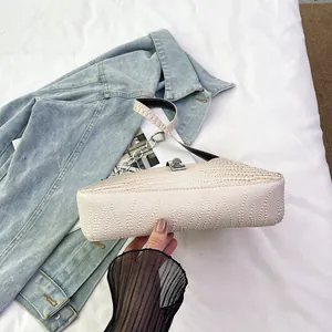 Close-up of cream white handbag with crocodile and caviar texture on a denim jacket