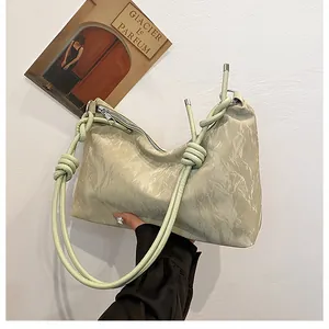 Close-up of light green hobo bag with knotted shoulder strap and pleated marble texture