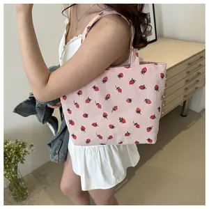 Detailed view of pink corduroy tote bag featuring retro strawberry pattern and sturdy straps