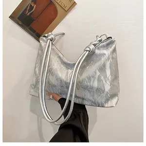 Detail of silver metallic tote bag featuring knotted strap and crinkled fabric texture